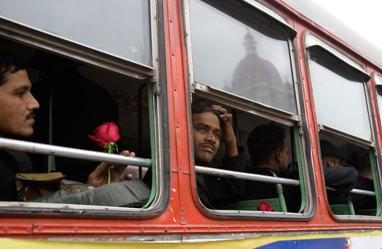An Indian commando soldier looks out at the Taj Mahal Hotel, seen reflected in a bus window, after he and fellow commandos were given roses and thanked by residents of Mumbai on Saturday following the end of a three-day rampage in the city.