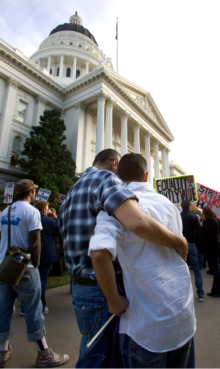Antonio Ceballos, left of Sacramento, Calif., and Armando Lara, right of Palmdale, Calif.,, embrace as they listen to speakers on the the west steps of the state Capitol in Sacramento, Calif., Saturday, Nov. 22.