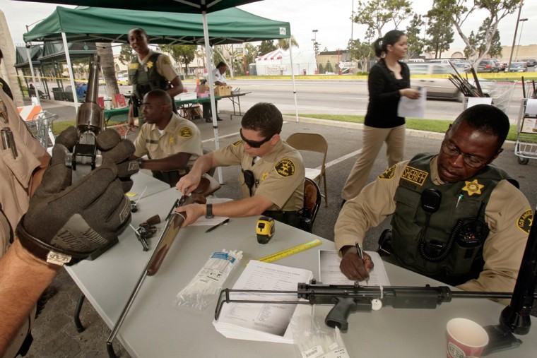 Image: Los Angeles County Sheriff Deputy Jeff Gordon, right, and colleagues examine and process weapons Dec. 7 in Compton, Calif.