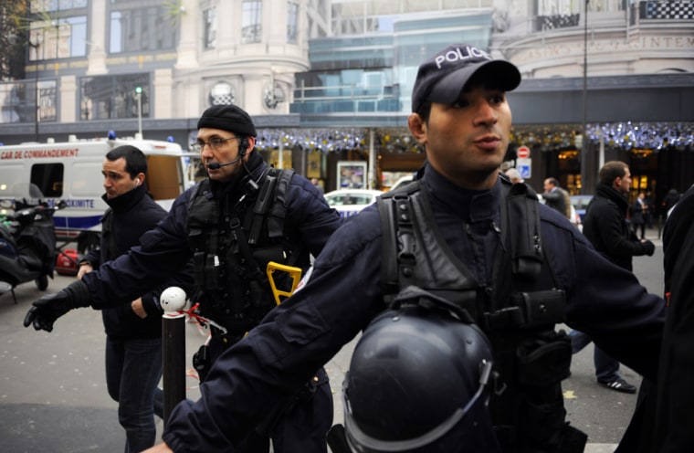 Image: French police secure the area outside a Paris department store after explosives were found