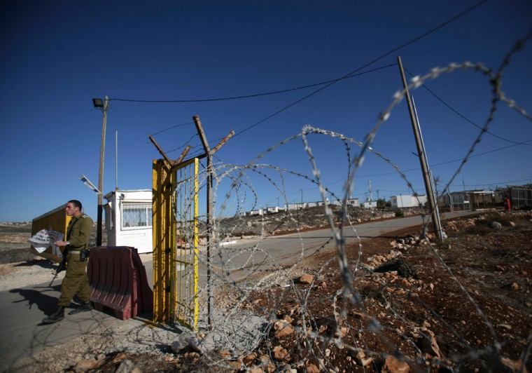 An Israeli soldier is seen at the entrance to the Jewish settlement of Migron, in the West Bank, Thursday, Dec. 11, 2008. The transformation of one piece of West Bank land from a Palestinian field into a Jewish settlement has roots in an unlikely place, Orange County, Calif., and in a document that a man supposedly signed more than 20 years after his death. (AP Photo/Dan Balilty)