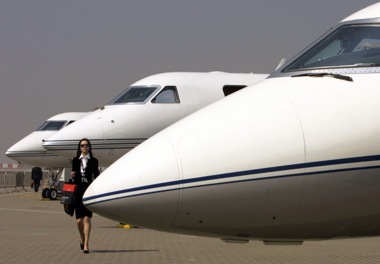 Image: A woman walks past Gulfstream business jets at the Asia Business Aviation Conference & Exhibition in Hong Kong.