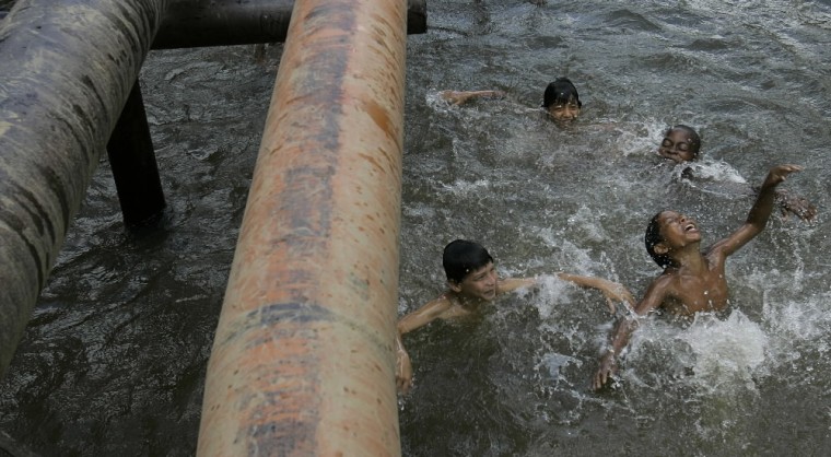 Children play in a river where oil pipes run above the surface in Ecuador's Sucumbios province, Aug. 4, 2008.  Ecuador's President Rafael Correa has sided squarely with the 30,000 plaintiffs, Indians and colonists, in a class-action suit, dubbed an Amazon Chernobyl by environmentalists, over the slow poisoning of a Rhode Island-sized expanse of rainforest with millions of gallons of oil and billions more of toxic wastewater. (AP Photo/Dolores Ochoa)