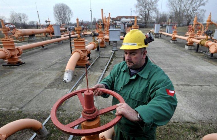 Image: A worker turns a tap at a gas receiving station