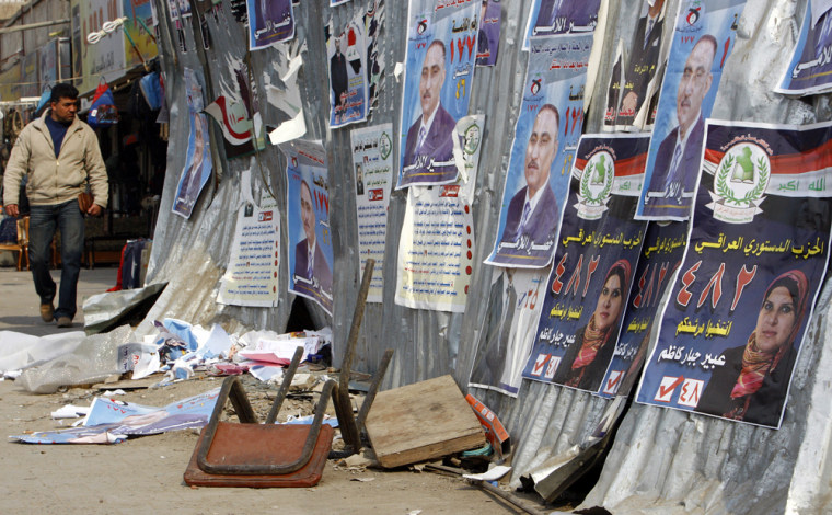 Image: A resident looks at election campaign posters in Baghdad