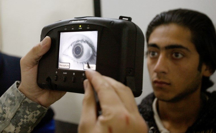 Image: A U.S. soldier akes a retina scan of a refugee