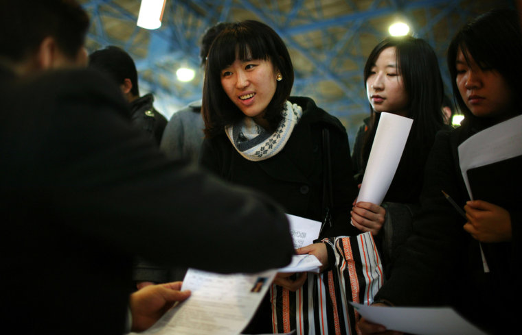 Image: Job seekers hand in their resumes at a job fair