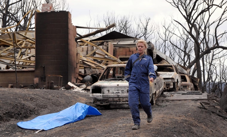 Image: Member of a Disaster Victim Identification Team walks on the site of a destroyed house at Steels Creek