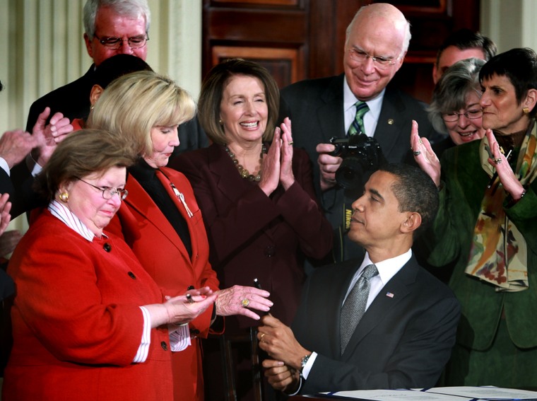 Image: U.S. President Barack Obama hands Lilly Ledbetter a pen