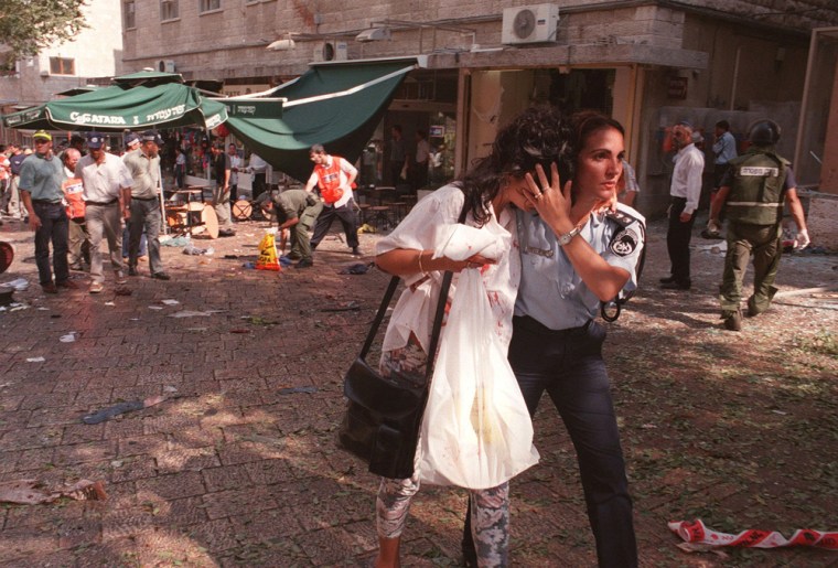 **ADVANCE FOR SUNDAY, FEB. 22** In this Sept. 4, 1997 file photo, an Israeli policewoman escorts a shocked woman  in downtown Jerusalem following a triple explosion at Jerusalem's Ben Yehuda pedestrian mall.  The Persepolis Fortification Tablets, on loan for decades to the University of Chicago's Oriental Institute,  are the subject of an unusual lawsuit. Victims of the Ben Yehuda pedestrian mall bombing in Israel in 1997 won a multimillion judgment against Iran and are now trying to collect by seizing the tablets and selling them.  (AP Photo/Bryan McBurney, file)