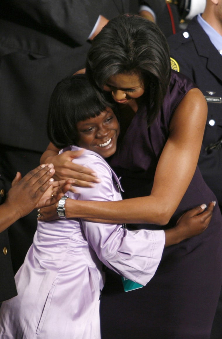 First lady Obama embraces student Bethea as they stand in gallery to watch Obama's address in Washington