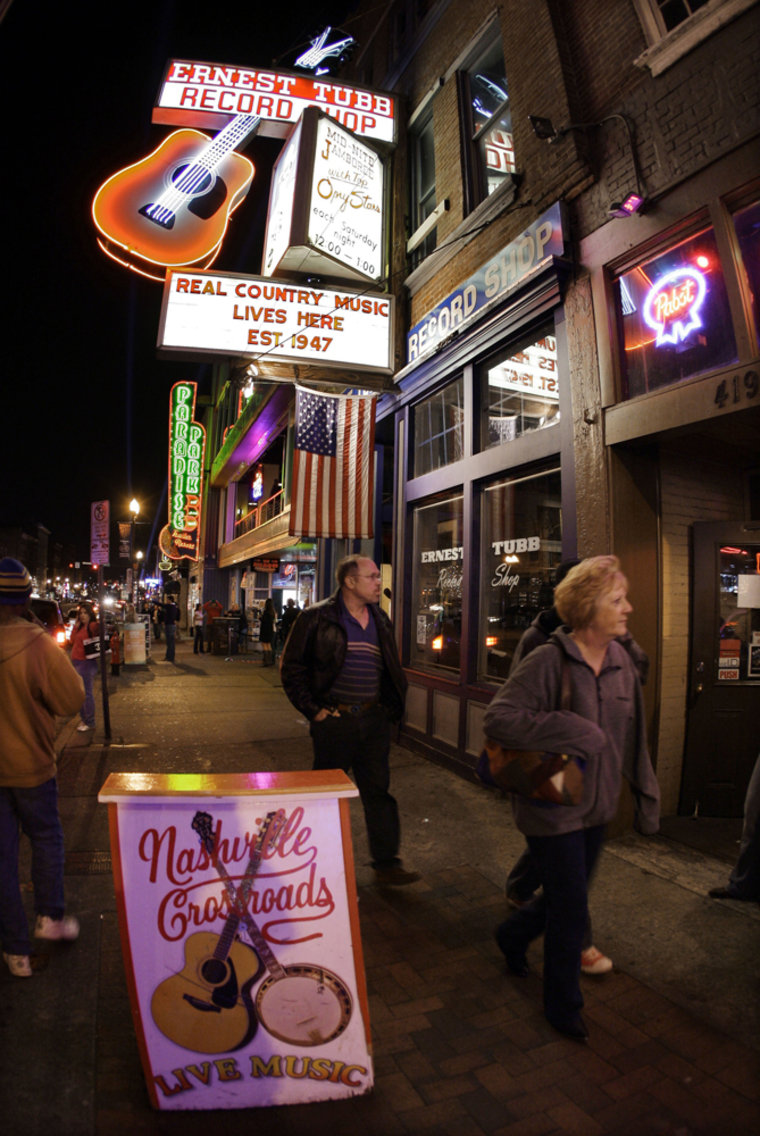 Image: People walk among the honky-tonks on Broadway in Nashville, Tenn.