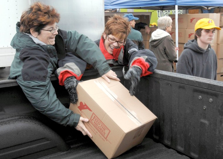 Truth Photo By J. Tyler Klassen Patti Elliott (left) and Kim Anglemire put a food box in the back of a truck at the Feed the Children food drop Tuesday at Concord Mall. The two were part of a large volunteer group that distributed food to about 5000 families.