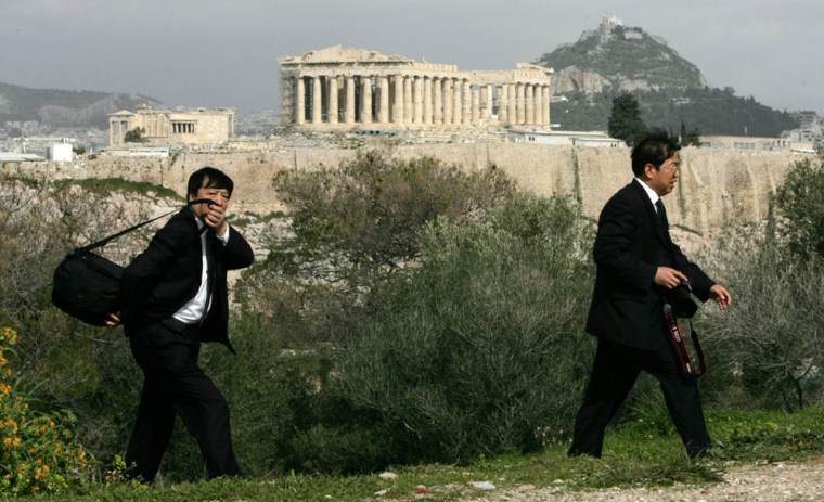 Image: tourists walk on Filopapos hill, in front of the ancient Parthenon