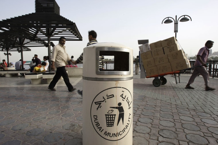 Image: People pass by a Dubai Municipality trash bin