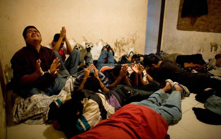 Handcuffed Central American migrants, who were being held hostage by a kidnap gang, react at soldiers, unseen, as they are freed in Reynosa, Mexico, Tuesday, March 17, 2009. According to authorities, more than 50 migrants were being held by the kidnap gang that was trying to extort their families in exchange for their freedom.(AP Photo/Alexandre Meneghini)