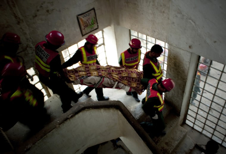 Image: Pakistani rescue members carry the body a police officer
