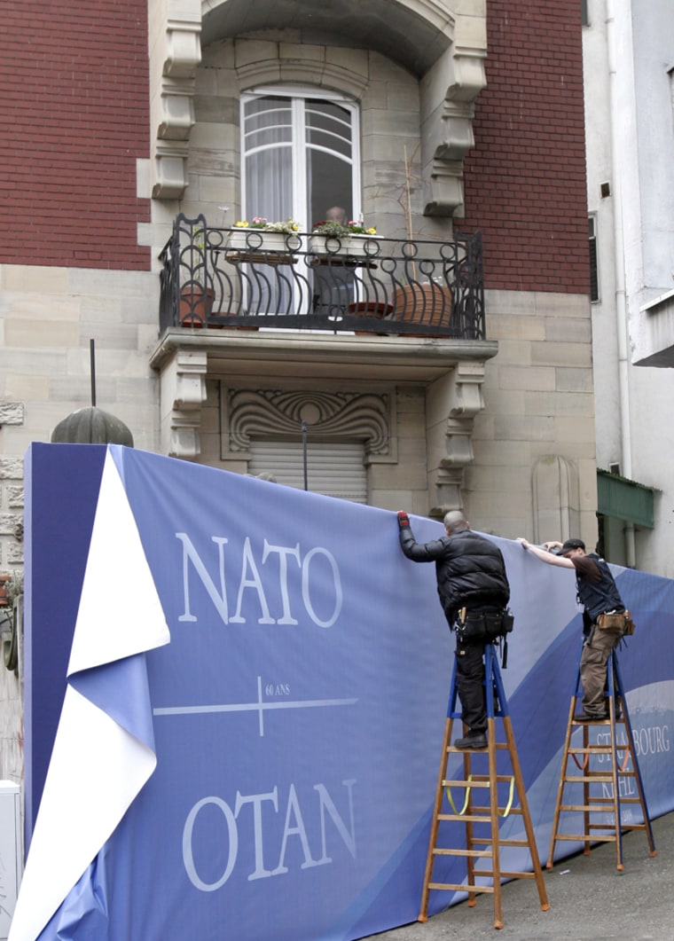 Image: workmen install a banner for the upcoming NATO summit