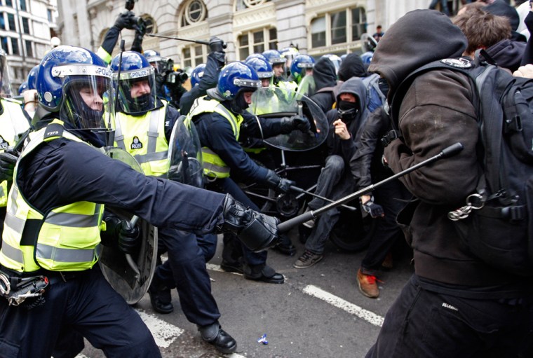 Image: Police in riot gear use their batons against demonstrators