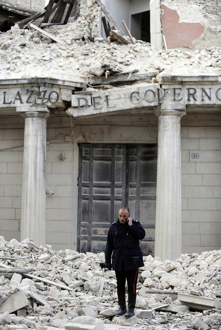 Image: A police officer in front of a damaged building in the center of the Abruzzo capital L'Aquila