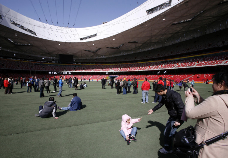 Image: Tourists walk and take photographs on the infield of the National Stadium