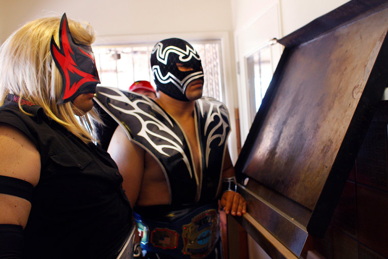Image: Wrestlers Renegado and Mr. Tempest look at an image of what they believe is \"Our Lady of Guadalupe\"