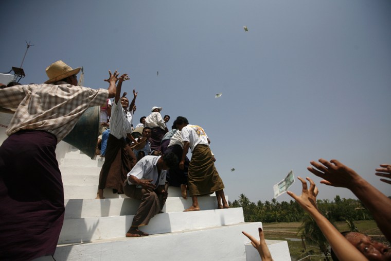 Villager try to catch money thrown by donors during the opening ceremony of the first cyclone shelter in Pyar Pon