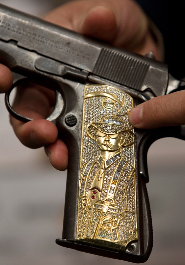 In this April 24, 2009 photo, an army officer shows a seized customized hand gun with an engraving in the butt grip at the Secretary of the Defense headquarters in Mexico City, Friday, April 24, 2009.  In all, the military has 305,424 confiscated weapons locked in vaults, just a fraction of those used by criminals in Mexico, where an offensive by drug cartels against the military has killed more than 10,750 people since December 2006.  The U.S. has acknowledged that many of the rifles, handguns and ammunition used by the cartels come from its side of the border. (AP Photo/Eduardo Verdugo)