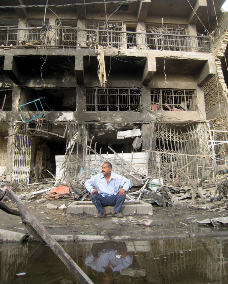 Image: Iraqi man sits outside a destroyed building after a car bomb