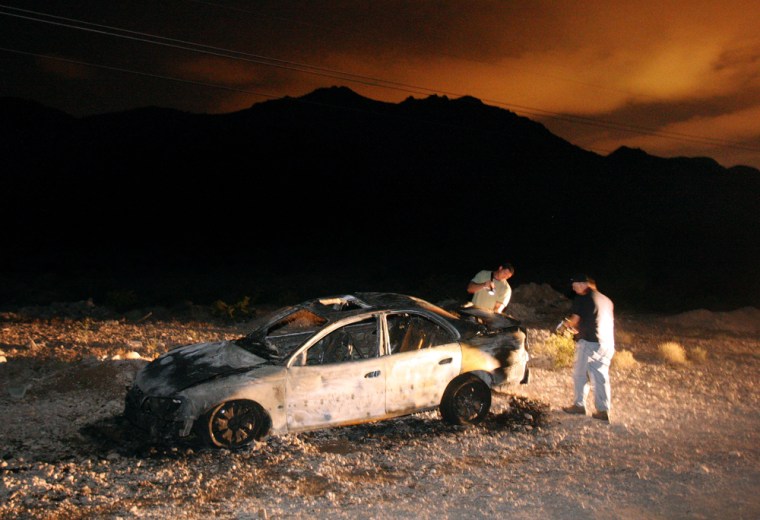 Image: Detectives investigating a burned out Cadillac in the desert outside Las Vegas