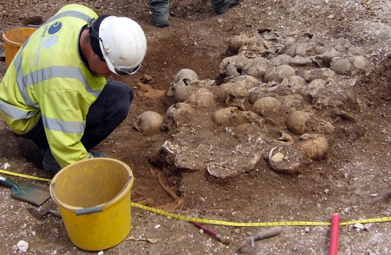 Image: A handout photograph shows an archaeologist digging at an ancient burial pit in Ridgeway, southern England