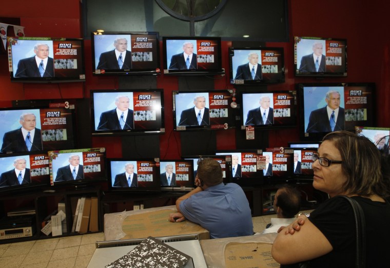Image: Israeli shopper stands in front of televisions broadcasting the speech of Israel's PM Netanyahu in Jerusalem