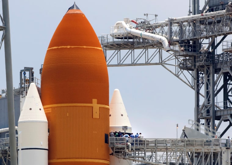 Image: NASA workers stand near external fuel tank and solid rocket boosters of Endeavour as it sits on launch pad  39A  at the Kennedy Space Center