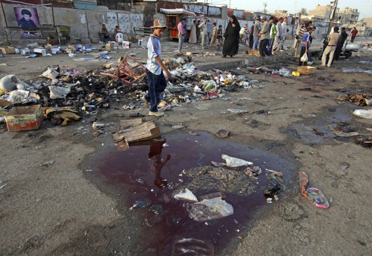 Image: Residents stand at the site of a bombing in the main Shiite district in Baghdad