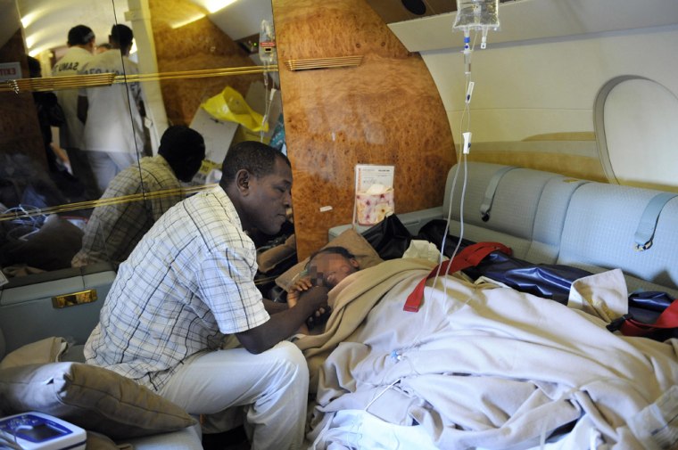Image: Bahia Bakari, 12, lies in a stretcher next to her father Kassim Bakari in a plane outside Paris