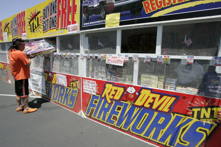 Image: A customer looks at a box of fireworks at a fireworks booth