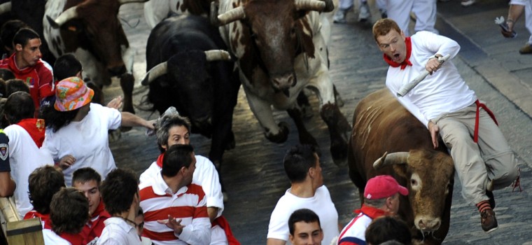 Image: A runner is tossed by a bull during the running of the bulls at the San Fermin festival in Pamplona