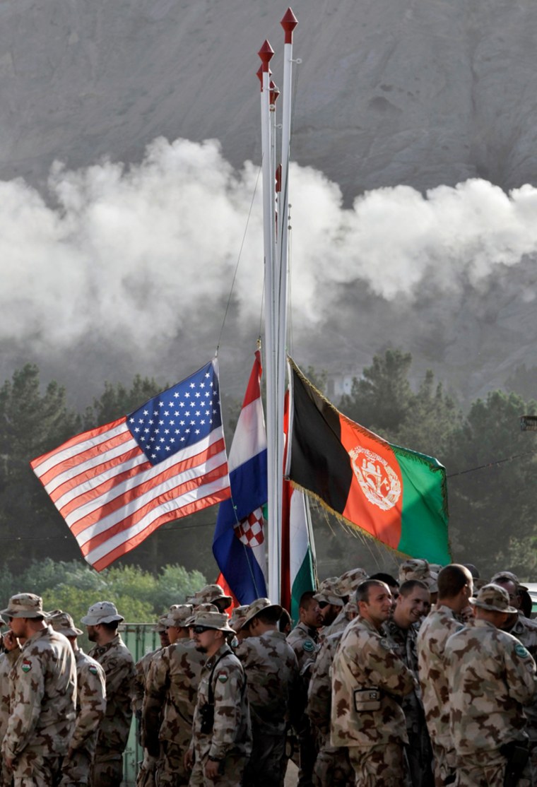 Image: The flags of Afghanistan, left, US, right, and other ISAF participating nations are kept on half mast remembering all the lost international troops