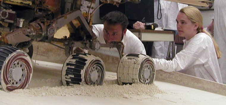 Mike Seibert and Sharon Laubach, engineers on the Mars Exploration Rover team at NASA's Jet Propulsion Laboratory, check the exact position of a test rover in preparation for a test of straight-backward driving.