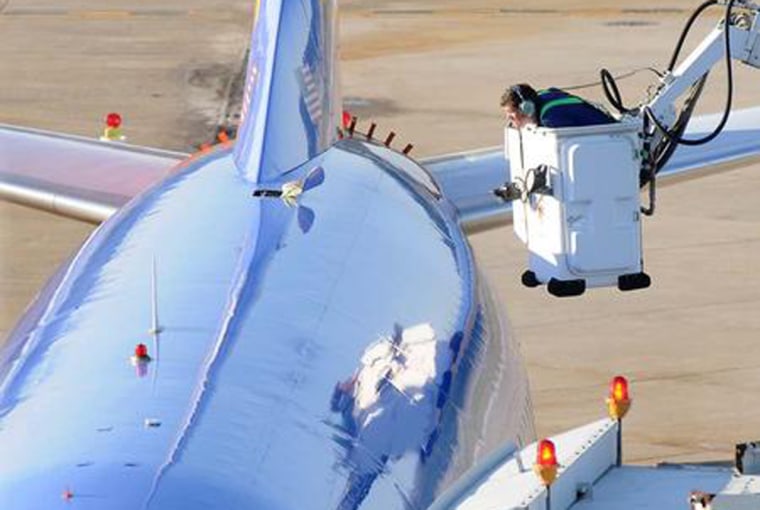 Image: An investigator inspects the hole on top of a Southwest Airlines jet forced to make an emergency landing in Charleston Monday.