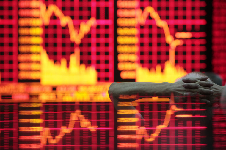 Image: A man reads information on an electronic screen at a brokerage house in Shanghai