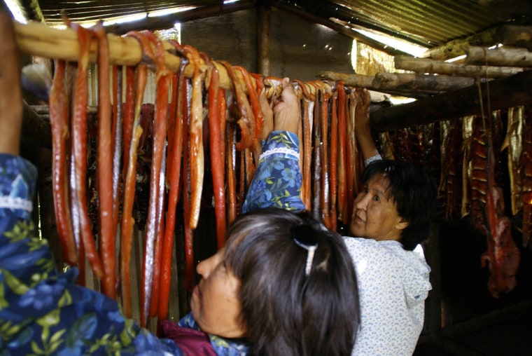 Image: Women move king salmon around the drying racks at a fish camp on the lower Yukon River in Alaska.