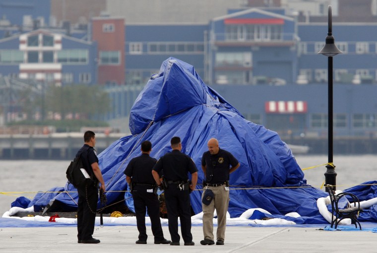 Image: Police stand guard in front of a helicopter wrapped in a blue tarp after it was recovered from the Hudson River, in Hoboken, N.J.