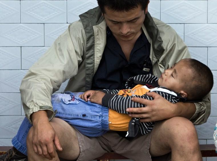 Image: A man holds his child while waiting for blood tests