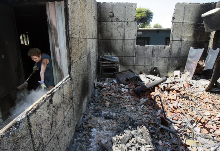 Image: A woman removes debris from her damaged house in Penteli suburb in Athens, Greece