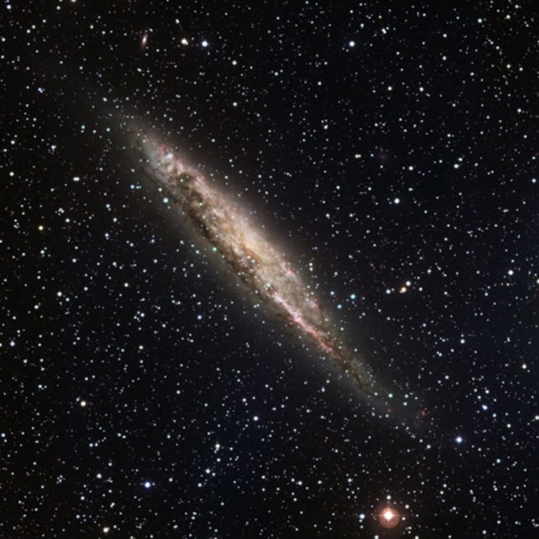 This image is an edge-on view of the spiral galaxy NGC 4945, which is thought to look much like the Milky Way, but with a brighter center that harbors a supermassive black hole. Sites of active stars formation in the image appear bright pink.