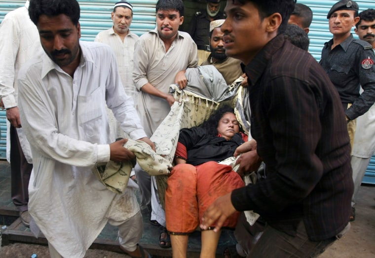 Image: A dead woman is removed from the scene of a stampede in Pakistan