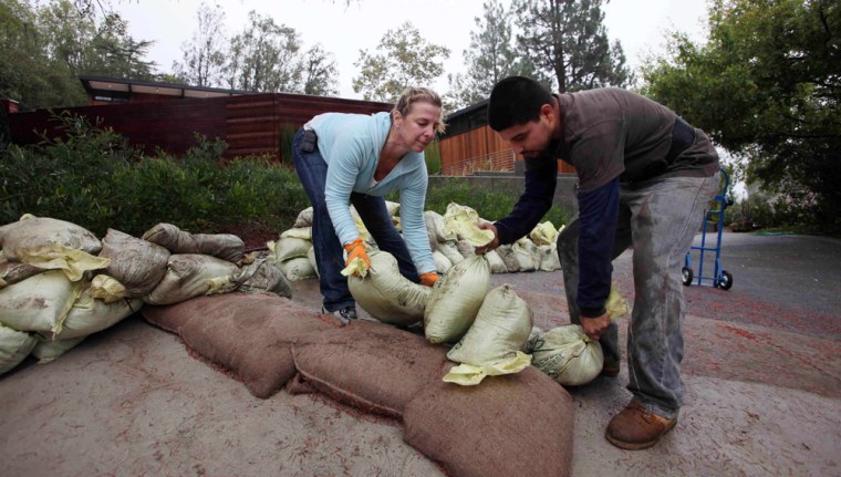 Image: People place sandbags in preparation for storm