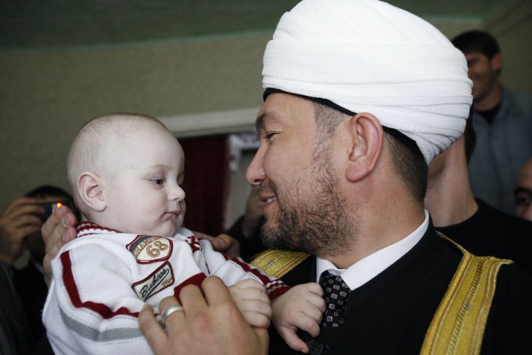 Image: A Muslim cleric holds baby Ali Yakubov at his house in Kizlyar in Russia's Dagestan Region