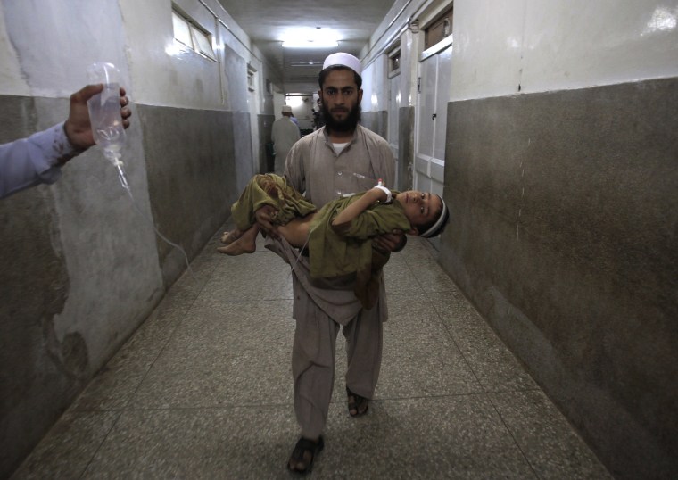 Image: A father carries his son, who was injured in a suicide bomb attack, through the halls of the Lady Reading hospital in Peshawar